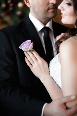 Yavaşça, gelini kucaklayan adam o göğsünde küçük bir gül tutuyor