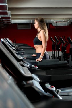 Spor salonunda bir koşu bandı üzerinde atletik bir kız