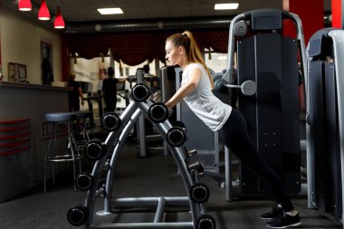 İnce kadın Barbell bir spor salonunda bir stand yaslanmış