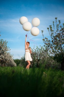 Alt görünümü mutlu kız beyaz holding bir yeşil alanda yüksek balonlar