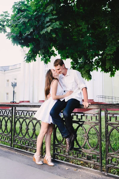 美妙的修长温柔的女孩亲吻她的男人坐在围栏比她高 — 图库照片