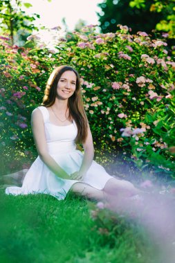 Çekici kız bir fotoğraf için onu dört küçük pembe çiçekler gülümseyerek