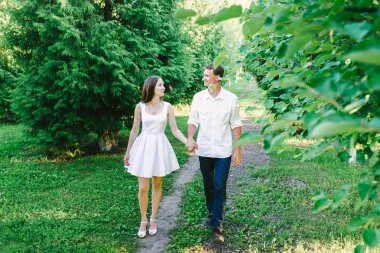 Genç çift birlikte tutuşup birbirimize yeşil ağaçlar her yerde onları aramaya yürüyüş