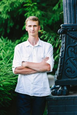 Kendine güvenen güzel adam elleriyle onun göğüs, yeşil ağaçlar arka planda üzerinde geçti. Doğada genç erkek portre