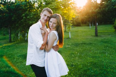 Yeşil bir orman, güneş ışığı ve ağaçlar arka planda sarılma çekici çift