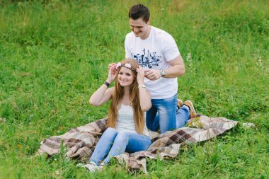 Adam ayakta oturma sevgilisinin arkasından dizlerinin üzerinde onlar gülümseyen ve kafasına pembe çiçek çelenk sabitleme