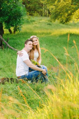 Genç bir çift birbirine yakın sarılma ve seyir bir şekilde kenara birlikte yeşil bir bahçe içinde oturuyor. Aşk hikayesi yeni evliler