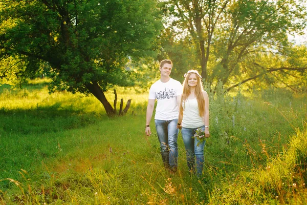 Couple in white shirts walking in a green forest together
