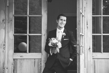 Yakışıklı damat açılan kapılar ayakta, bir kenara gülümseyen arıyorum güzel düğün buket ile siyah beyaz resim