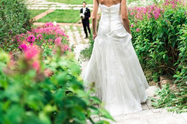 Genç gelin yaygın olarak gülümseyen damat, pembe çiçekler her yerde onları merdiven geliyor