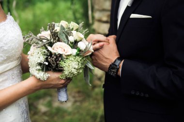 Yakın, düğün buket aralarında, el ele tutuşarak ayakta yeni evliler