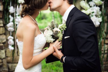 Yeni evliler yavaşça, el ele tutuşarak öpüşme