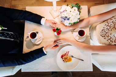 Kafe, üstten görünüm çifte düğün. Erkek ve kadının ellerini ve kahve bardağı masanın üzerine