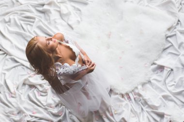 Genç seksi kız soyunuyor üst katında, gözleri kapalı, beyaz bez izole. Güzel bir genç kadının portresi üstten görünüm