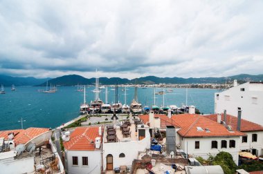 Deniz, dağlar kadar arkadaki kapsayan büyük bulutlu gökyüzü yakın bir sahil kasabası görünümünü