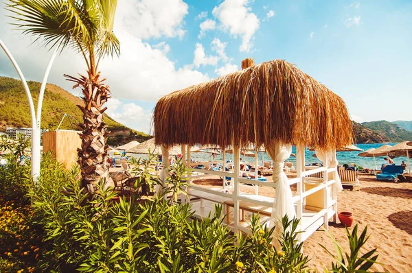 Bir Thatched çardak sıcak kum plajındaki, yaz tatili bir deniz manzarası