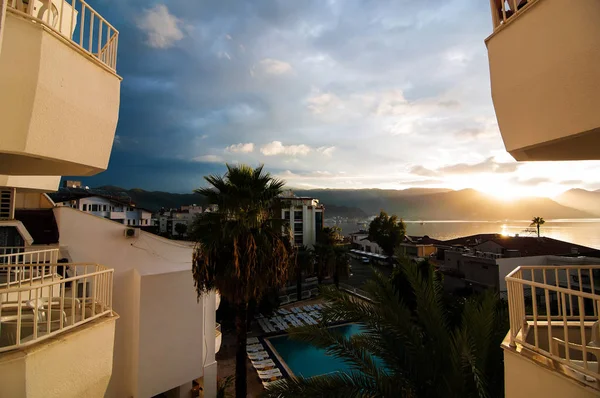 Breathtaking view of sea resort from a fine hotel room, pools, palms, water and sunset in the mounts