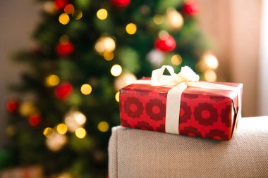 Noel hediyesi kağıt ve beyaz bir Şerit sarma bir kırmızı parlak süslemeleri arka planda, tatil atmosferinde bulanık. Noel şenlikli arka planda, boşaltmak hediyesi