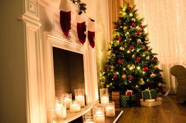 Kış tatil mumlar ve mevcut oyuncaklar ile tam ışıklar ve oyuncaklar sevimli bir şömine yakınındaki bir Noel ağacı ile sıcak bir odada atmosfer. Noel iç. Yeni yıl tasarım