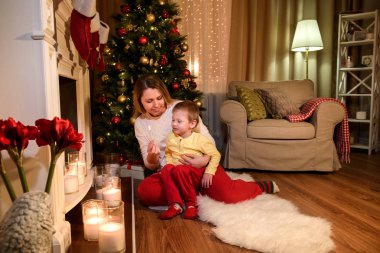 Maçı, yeni yıl atmosfer bir oturma odasında uçurmak için oğlunu soran annesi gülümseyerek. Genç Anne ve oğlu bir şömine Noel tarafından