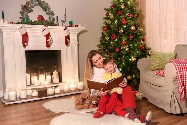 Family of mother and son reading a big book in a new year decorated room in the winter for the Christmas holidays. Happy family New Year concept