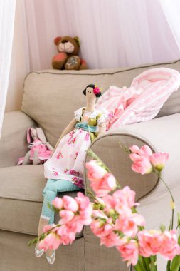 El yapımı kukla kumaş yumuşak rahat koltukta oturan bir resim ilk planı üzerinde pembe çiçekler