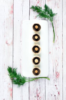 Mükemmel özdeş bir satýr adil ahşap bir masa kopya alanı üzerinde beyaz tabak içinde aşağı yalan baş mantar. Üstten görünüm