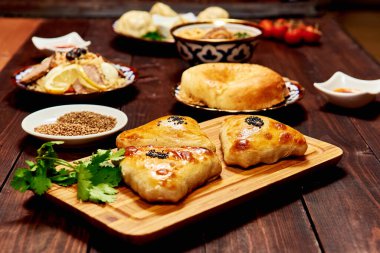 Kafkas yemekleri karanlık arka plan. Samsa, plov, noodle, et, lavaş, manti, domates, sos. Kafkas restoranı konsepti. Metin için boşluk.