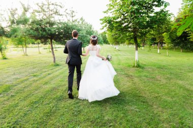 Yeşil bir yaz bahçesinde kaçan evli bir çift. Mutlu gelin ve damat yaz çayırında koşup dans ediyor. Romantik Evli Genç Aile