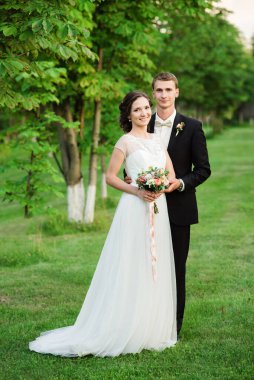 Mutlu genç çift yeni evlendi. Düğün günü. Mutlu çift yeşil bir bahçede mutlu bir şekilde gülümsüyor.