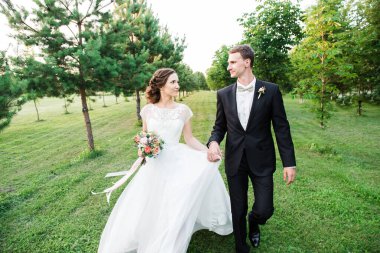 Yeşil bahçede el ele tutuşup birbirlerine bakan hoş bir çift.