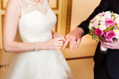 Gelin damadın parmağına alyans takıyor. Bir çift evleniyor. Evlilik yüzükleri.