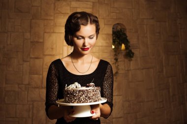 Düşünceli kız doğum günü pastası tutuyor, özel durumlarda lezzetli tatlılar pişiriyor. Karanlık gece elbisesi