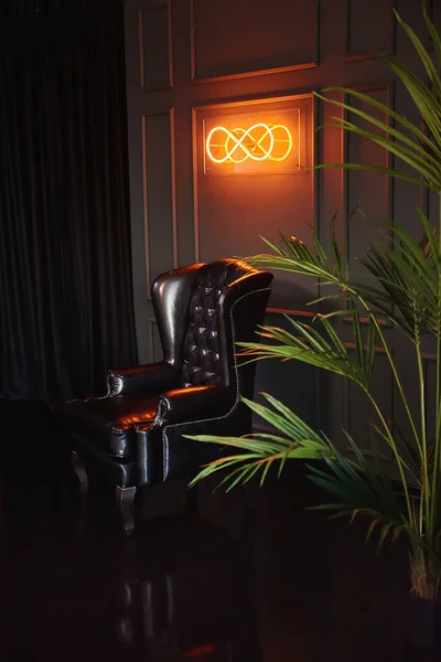房间里的黑色经典扶手椅和棕榈树 无限大绿墙的霓虹灯 — 图库照片