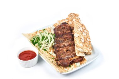 Kemiğin üzerinde domuz kaburgası şişi ve yakın plan bir restoranda sos. Beyaz bir tabakta soğanlı şişler ve pide ekmeği var..