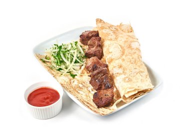 Lokantada soslu dana barbeküsü. Beyaz bir tabakta soğanlı şişler ve pide ekmeği..