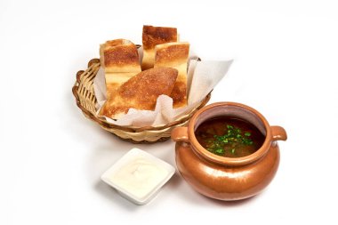 Bir dilim ekmek ve ekşi kremayla servis edilen bir çömlek çorba. Bir kafede, restoranda menü için yemek servisi yapıyorum. Beyaz arkaplanda izole