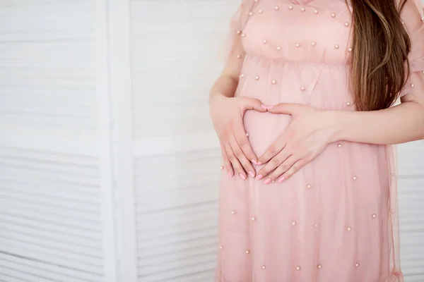 美丽的孕妇抱着肚子 心形像的剪影 一名孕妇的特写镜头触及她的腹部在前景 — 图库照片