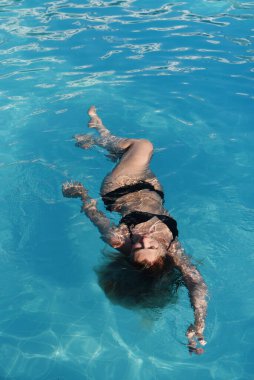 Güzel genç bayan spa havuzunda dinleniyor, kendine bakıyor. Uçan vücut konsepti, sırt tedavisi. Sakinlik kavramı.