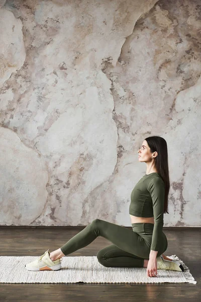 年轻迷人的女人穿着运动服 开始她的一天工作在瑜伽工作室附近的墙壁背景 健康的生活方式概念 关节和韧带的弹性概念 广告空间 — 图库照片