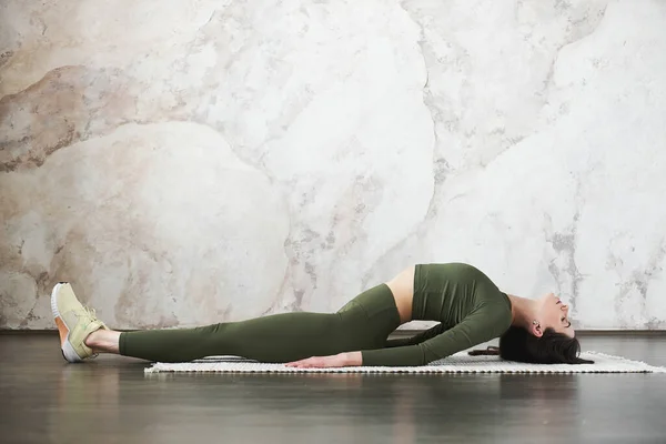 年轻迷人的女人穿着运动服 开始她的一天做伸展练习 做脊柱和肩膀柔韧的运动 在瑜伽工作室锻炼 健康的生活方式概念 复制空间 — 图库照片