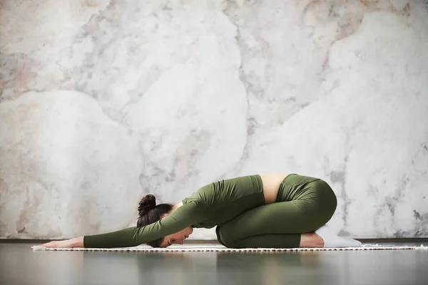 漂亮的年轻模特儿在家里锻炼身体 在黑木地板上为脊柱做瑜伽练习 躺在儿童峰 芭蕾莎娜姿势 练习后休息 侧视图 — 图库照片