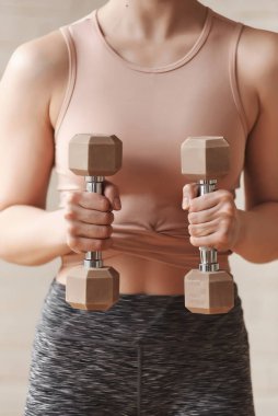 Spor kıyafetleri giymiş, ağırlık kaldıran spor yapan çekici bir kadının spor yaparken çekilmiş görüntüsü. Sabah egzersizleri kas gücü için. Spor ve eğlence konsepti, dikey fotoğraf, yakın çekim.