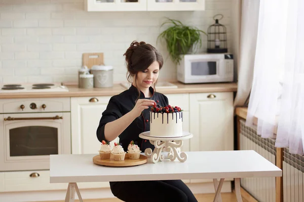 年轻的女性专业糖果店在厨房里用草莓 覆盆子 黑莓和蓝莓装饰一层滴下蛋糕 复制空间 家庭工作概念 — 图库照片
