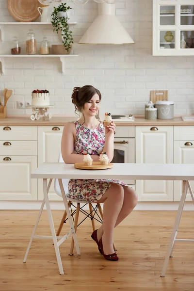 年轻的微笑的女人坐在桌旁 在白色厨房里端着美味的蛋糕 上面有奶油和浆果 体重减轻概念 复制空间 — 图库照片