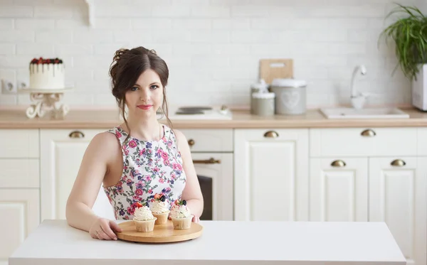 年轻的女人坐在桌旁 手里拿着一个盘子 里面有一个美味的蛋糕 里面有奶油和浆果 放在一个白色的厨房里 体重减轻概念 复制空间 — 图库照片