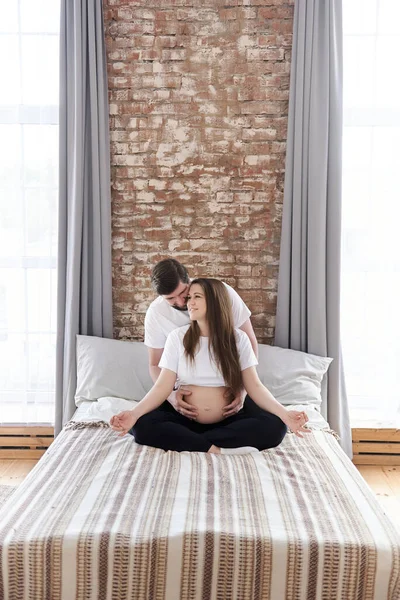 Lachende Zwangere Vrouw Zittend Lotuspositie Een Bed Terwijl Haar Man — Stockfoto