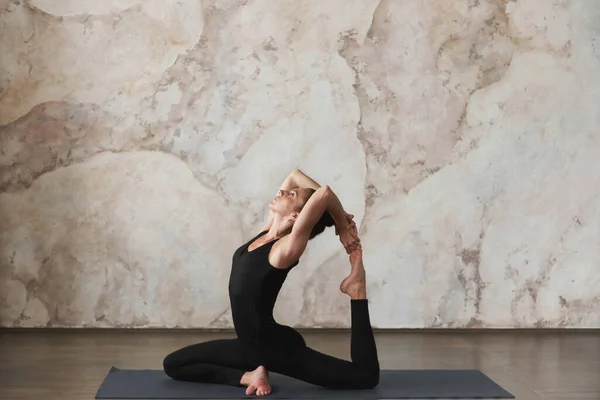 强壮的中年女子练习瑜伽 做Vrischikasana 蝎子运动以增强背部肌肉的柔韧性 身穿黑色运动服 健康生活概念 — 图库照片