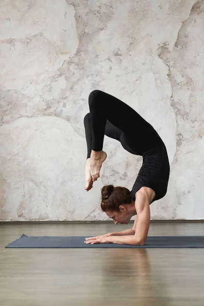 强壮的中年有运动魅力的女子练习瑜伽 做Vrischikasana 蝎子运动 手倒立姿势 身穿黑色运动服 健康生活理念 体操和家庭健身 — 图库照片