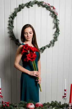 Arkasında kırmızı buket ve Noel çelengi olan nazik bir genç kızın resmi. Noel odası iç tasarımı.